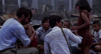 Movie still from “The Killing Fields” (1984), directed by Roland Joffé – A group of people sitting on the ground; Medium shot, Over the shoulder angle