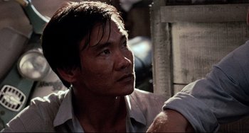 Movie still from “The Killing Fields” (1984), directed by Roland Joffé – A person wearing a white shirt; Close Up shot, Over the shoulder angle