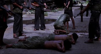 Movie still from “The Killing Fields” (1984), directed by Roland Joffé – A group of men are laying on the ground; Wide shot, High angle