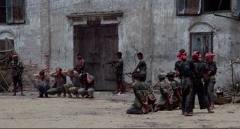 Movie still from “The Killing Fields” (1984), directed by Roland Joffé – A group of men standing in front of a building; Extreme Wide shot, High angle