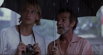 Movie still from “The Killing Fields” (1984), directed by Roland Joffé – A man holding an umbrella over another man's face; Close Up shot, Low angle