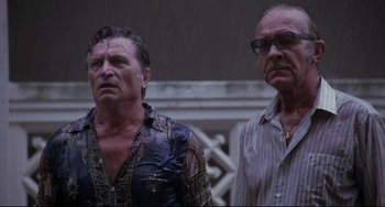 Movie still from “The Killing Fields” (1984), directed by Roland Joffé – Two men standing next to each other in the rain; Medium shot, Low angle