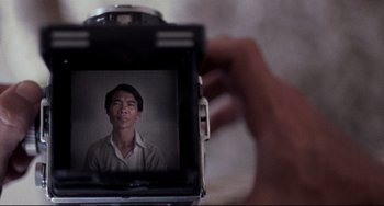 Movie still from “The Killing Fields” (1984), directed by Roland Joffé – A person taking a picture of a man with a camera; Extreme Close Up shot, Over the shoulder angle
