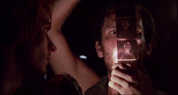 Movie still from “The Killing Fields” (1984), directed by Roland Joffé – A man looking at another man holding up a picture; Close Up shot, Over the shoulder angle