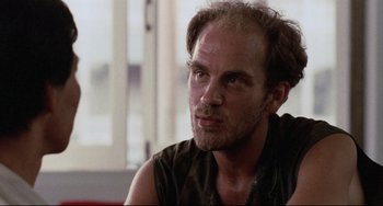 Movie still from “The Killing Fields” (1984), directed by Roland Joffé – A person sitting in front of a window; Close Up shot, Low angle