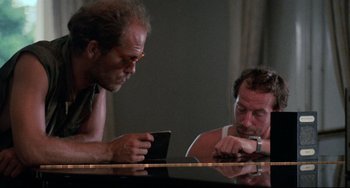 Movie still from “The Killing Fields” (1984), directed by Roland Joffé – Two men sitting at a table looking at a tablet; Close Up shot, Over the shoulder angle