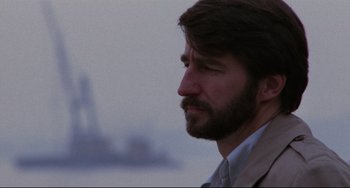 Movie still from “The Killing Fields” (1984), directed by Roland Joffé – A person wearing a suit and tie; Close Up shot, Over the shoulder angle
