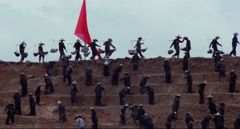 Movie still from “The Killing Fields” (1984), directed by Roland Joffé – A group of men in black suits and hats on top of a dirt hill; Extreme Wide shot, High angle
