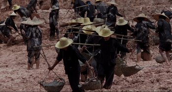 Movie still from “The Killing Fields” (1984), directed by Roland Joffé – A group of people in black suits and hats; Wide shot, High angle