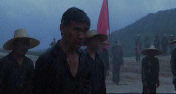 Movie still from “The Killing Fields” (1984), directed by Roland Joffé – A group of men standing next to each other on a dirt road; Medium shot, Low angle