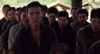 Movie still from “The Killing Fields” (1984), directed by Roland Joffé – A group of men standing next to each other in a line; Medium shot, Over the shoulder angle