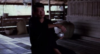 Movie still from “The Killing Fields” (1984), directed by Roland Joffé – A man sitting on the ground with a bowl in his hand; Medium shot, Low angle