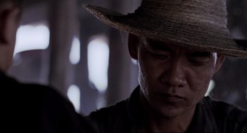 Movie still from “The Killing Fields” (1984), directed by Roland Joffé – A person wearing a straw hat; Close Up shot, Low angle