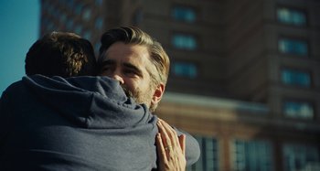 Movie still from “The Killing of a Sacred Deer” (2017), directed by Yorgos Lanthimos – A man hugging another man in front of a tall building; Close Up shot, Over the shoulder angle
