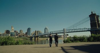 Movie still from “The Killing of a Sacred Deer” (2017), directed by Yorgos Lanthimos – Two people walking on a path near a river; Extreme Wide shot, Over the shoulder angle