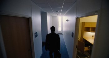 Movie still from “The Killing of a Sacred Deer” (2017), directed by Yorgos Lanthimos – A man in a black suit is walking down a hallway; Wide shot, High angle