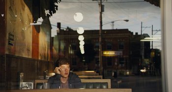 Movie still from “The Killing of a Sacred Deer” (2017), directed by Yorgos Lanthimos – A man sitting at a table in front of street lights; Medium shot, Over the shoulder angle