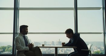 Movie still from “The Killing of a Sacred Deer” (2017), directed by Yorgos Lanthimos – Two men sitting at a table in front of a window; Wide shot, Over the shoulder angle