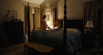 Movie still from “The Killing of a Sacred Deer” (2017), directed by Yorgos Lanthimos – A woman standing on a bed in front of a window; Wide shot, High angle