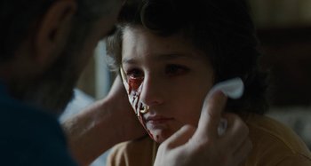 Movie still from “The Killing of a Sacred Deer” (2017), directed by Yorgos Lanthimos – A young girl with an injured eye is being examined by an eye doctor; Close Up shot, Over the shoulder angle