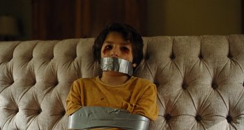 Movie still from “The Killing of a Sacred Deer” (2017), directed by Yorgos Lanthimos – A young boy with duct tape around his mouth; Close Up shot, High angle