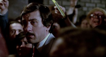 Movie still from “The King of Comedy” (1982), directed by Martin Scorsese – A person wearing a suit and tie; Close Up shot, Over the shoulder angle