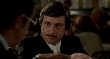 Movie still from “The King of Comedy” (1982), directed by Martin Scorsese – A person wearing a suit and tie; Close Up shot, Over the shoulder angle