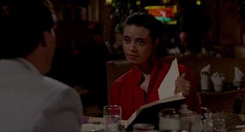 Movie still from “The King of Comedy” (1982), directed by Martin Scorsese – A woman sitting at a table in a restaurant holding an open book; Close Up shot, Over the shoulder angle
