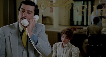 Movie still from “The King of Comedy” (1982), directed by Martin Scorsese – A man talking on a phone while a woman looks on; Medium shot, Over the shoulder angle