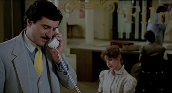 Movie still from “The King of Comedy” (1982), directed by Martin Scorsese – A man talking on a phone while a woman sits in the background; Medium shot, Low angle