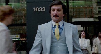 Movie still from “The King of Comedy” (1982), directed by Martin Scorsese – A man in a suit and tie standing in front of a building; Close Up shot, Low angle