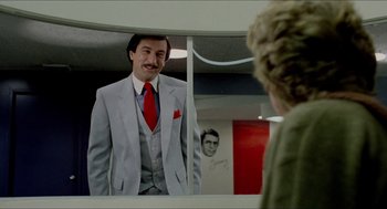 Movie still from “The King of Comedy” (1982), directed by Martin Scorsese – A man wearing a suit and tie in front of a mirror; Medium shot, Over the shoulder angle