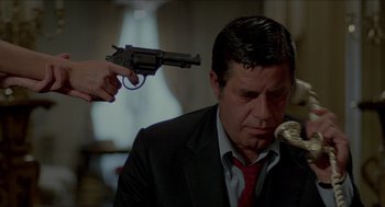 Movie still from “The King of Comedy” (1982), directed by Martin Scorsese – A man in a suit and tie with a gun pointed at him; Medium shot, Over the shoulder angle