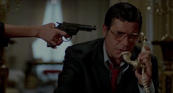 Movie still from “The King of Comedy” (1982), directed by Martin Scorsese – A man in a suit and red neck tie holding a gun; Close Up shot, Low angle