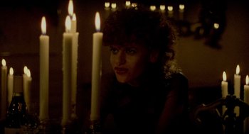 Movie still from “The King of Comedy” (1982), directed by Martin Scorsese – A woman sitting in front of a group of lit candles; Close Up shot, Low angle