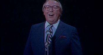 Movie still from “The King of Comedy” (1982), directed by Martin Scorsese – An older man wearing a suit and tie; Medium shot, Low angle