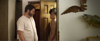 Movie still from “The Kings of Summer” (2013), directed by Jordan Vogt-Roberts – A man and a young boy standing next to each other in front of a door; Medium shot, Over the shoulder angle