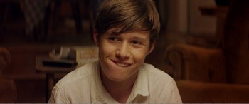 Movie still from “The Kings of Summer” (2013), directed by Jordan Vogt-Roberts – A young man smiling for the camera; Close Up shot, Over the shoulder angle