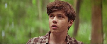 Movie still from “The Kings of Summer” (2013), directed by Jordan Vogt-Roberts – A young man with brown hair and a plaid shirt looking to his left; Close Up shot, Low angle