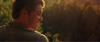 Movie still from “The Kings of Summer” (2013), directed by Jordan Vogt-Roberts – A young man smiles brightly as the sun goes down; Close Up shot, Over the shoulder angle