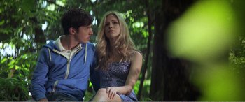 Movie still from “The Kings of Summer” (2013), directed by Jordan Vogt-Roberts – A man and a woman sitting on a bench in the woods; Medium shot, Low angle