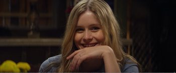 Movie still from “The Kings of Summer” (2013), directed by Jordan Vogt-Roberts – A beautiful young lady sitting in front of a bookshelf; Close Up shot, Over the shoulder angle