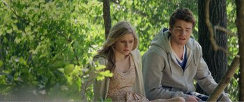 Movie still from “The Kings of Summer” (2013), directed by Jordan Vogt-Roberts – A woman sitting next to a man on a park bench; Medium shot, Low angle