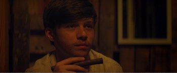 Movie still from “The Kings of Summer” (2013), directed by Jordan Vogt-Roberts – A young man holding a cigar in his hand; Close Up shot, Over the shoulder angle