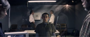 Movie still from “The Kings of Summer” (2013), directed by Jordan Vogt-Roberts – A man standing in front of two other men in a room; Medium shot, Over the shoulder angle