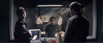 Movie still from “The Kings of Summer” (2013), directed by Jordan Vogt-Roberts – A group of men standing around a computer desk; Medium shot, Over the shoulder angle