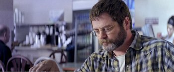 Movie still from “The Kings of Summer” (2013), directed by Jordan Vogt-Roberts – A man with a beard and glasses looking down at a book; Close Up shot, Over the shoulder angle