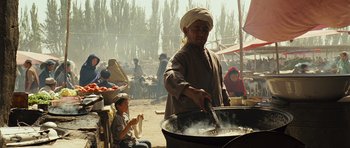 Movie still from “The Kite Runner” (2007), directed by Marc Forster – A man cooking food in a large pot; Medium shot, Over the shoulder angle