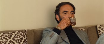 Movie still from “The Kite Runner” (2007), directed by Marc Forster – A man sitting on a couch drinking a cup of coffee; Close Up shot, Low angle