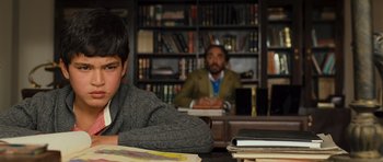 Movie still from “The Kite Runner” (2007), directed by Marc Forster – Two people sitting at a table in front of a book shelf; Medium shot, Over the shoulder angle